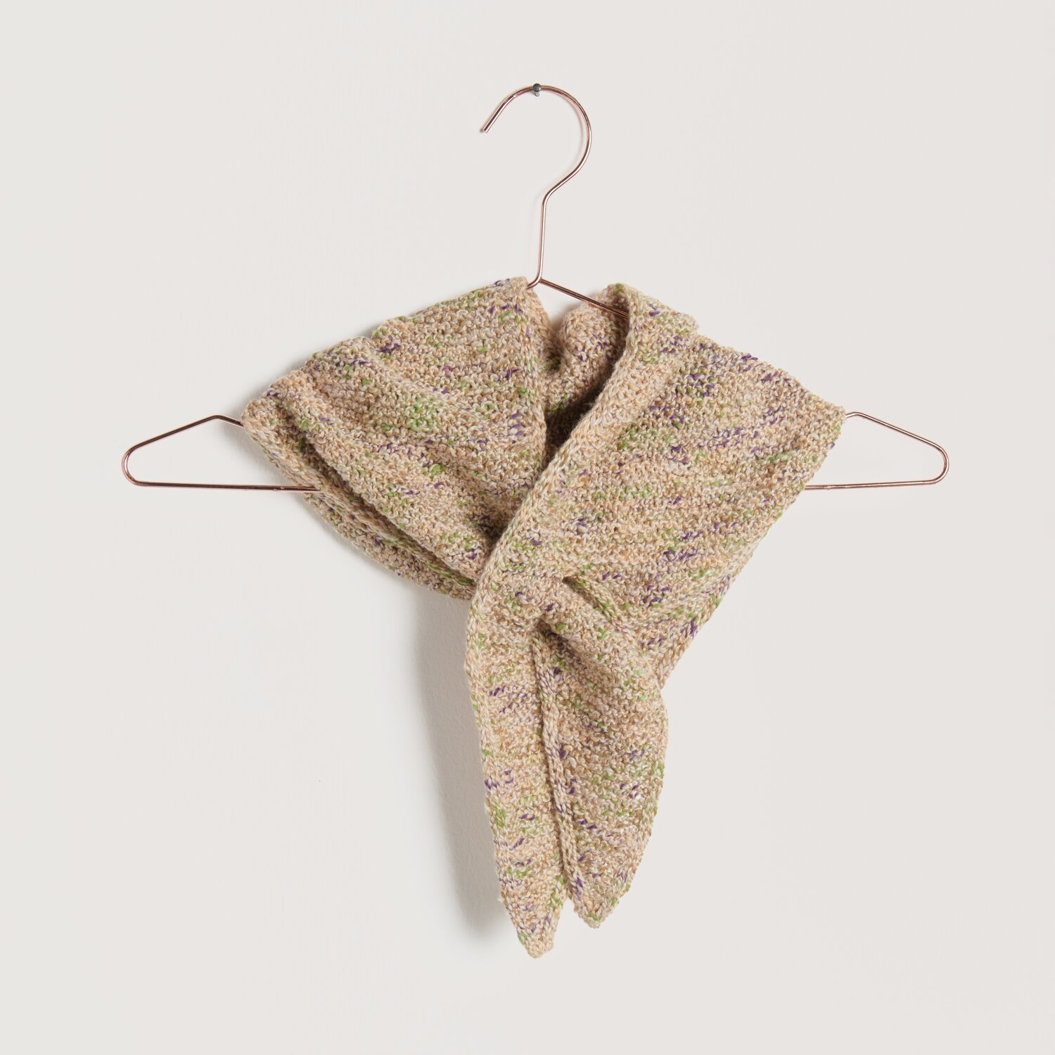 Lovewool No. 22 Frühjahr-Sommer Schal in pfirsichfarbenem Strick, elegant drapiert auf einem Kupferbügel.