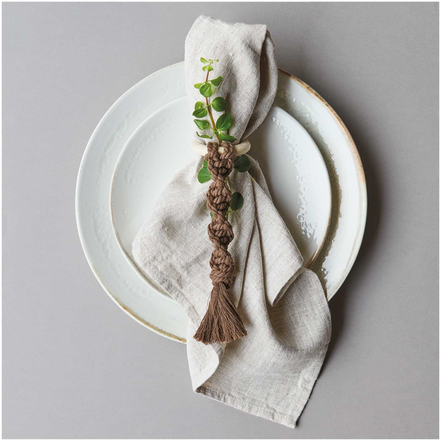 Creative Cotton Cord Makramee-Garn: Elegantes Tischset mit Serviette, verziert mit Makramee-Knoten in Mokka, auf weißem Teller arrangiert.