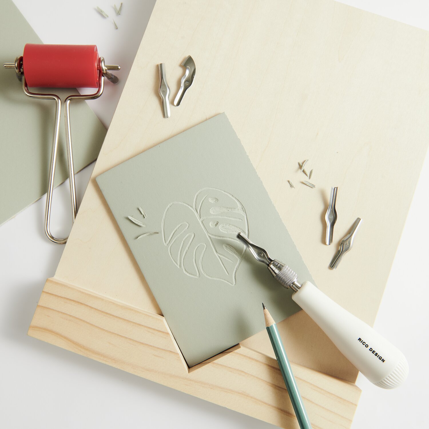 Schnitzblockhalter mit grauer Platte, Schnitzwerkzeug und roter Walze von Rico Design. Ideal für kreative Projekte.