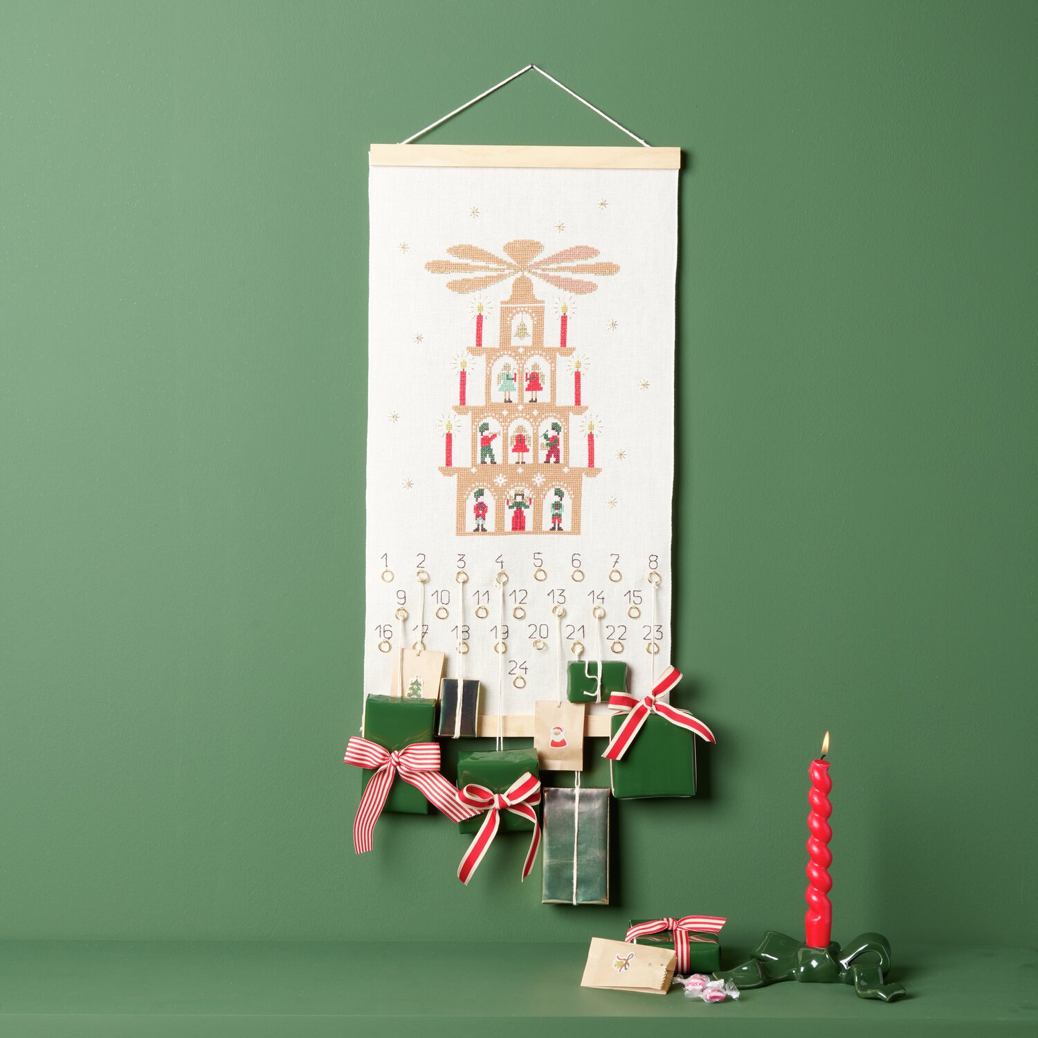Stickpackung Adventskalender Lichterpyramide von Rico Design zeigt eine dekorative Pyramide auf einem grünen Hintergrund mit roten Akzenten.