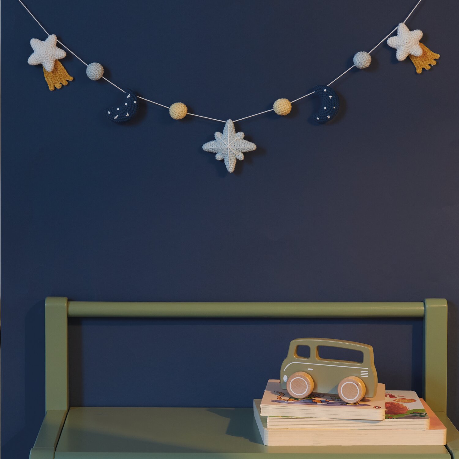Ricorumi Glow In The Dark Girlande mit Sternen und Monden vor nachtblauer Wand, dekorativ über grünem Regal mit Spielzeugauto.
