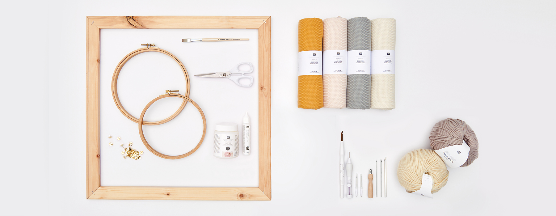 Punch Needle, Stickrahmen, Stoffrollen und Garn arrangiert auf grauem Hintergrund