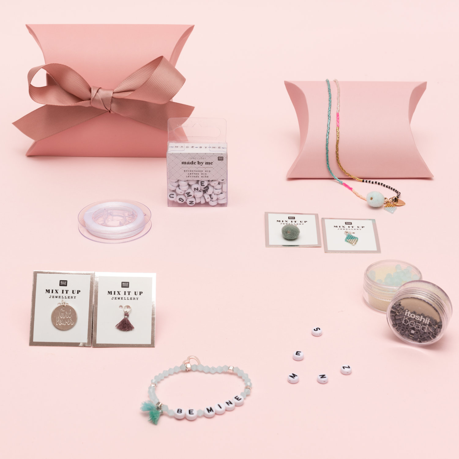 Mehrere pinke Geschenkschachteln mit Schmuckperlen, Schmuckband und verschiedenen Anhängern. Fotosetting rosa Wand.