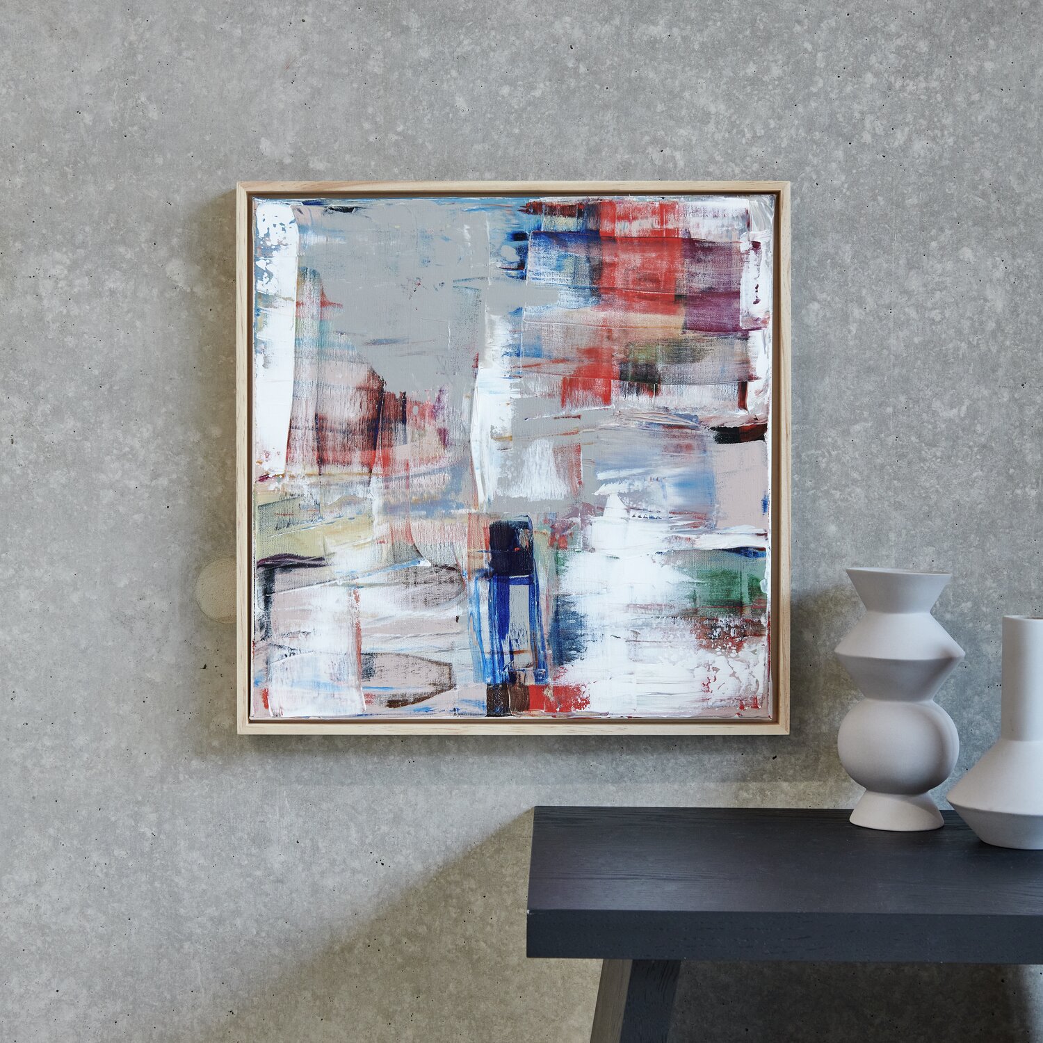 ART Künstler Acrylfarben-Set Erdfarben 12x12ml: Abstraktes Gemälde in Rot, Blau und Weiß an grauer Wand über dunklem Tisch.