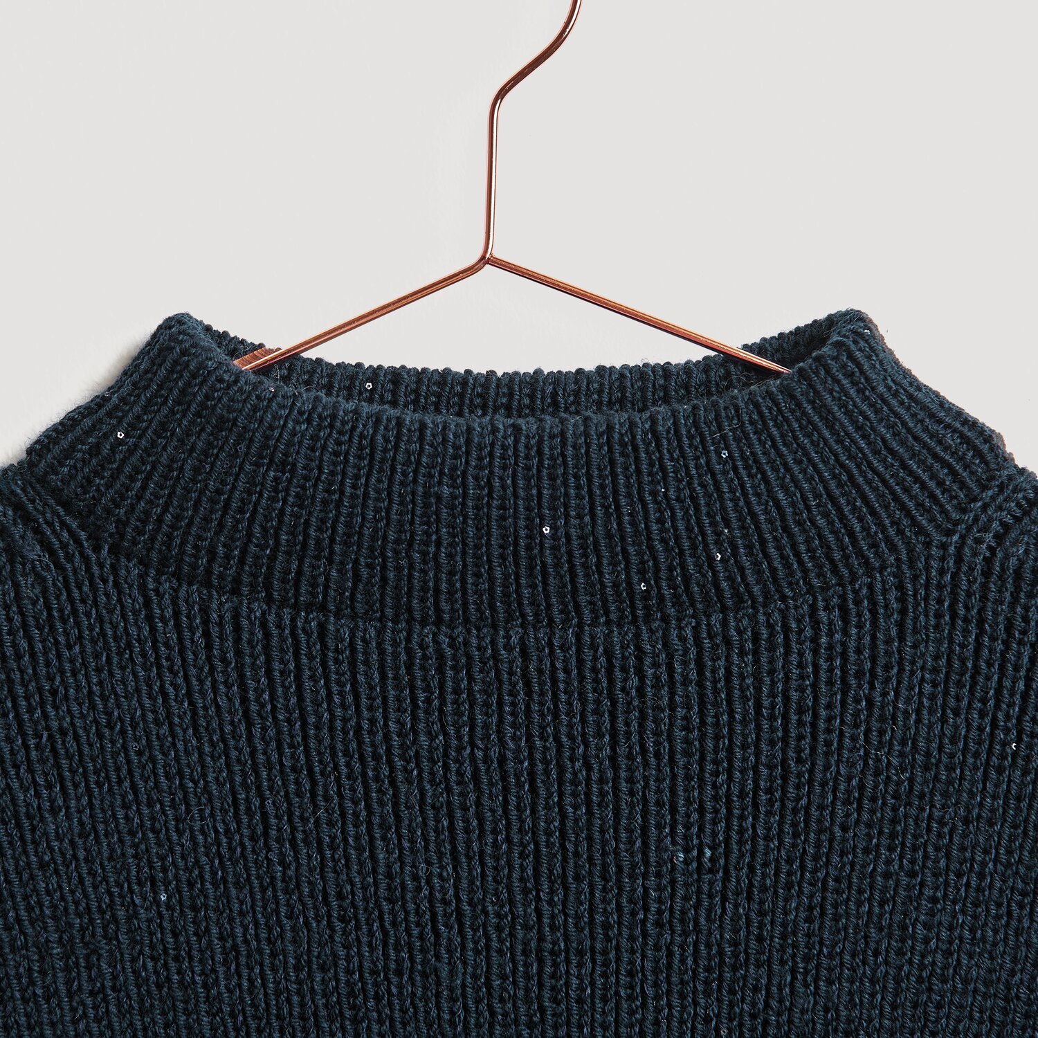 Die Neue Masche No. 13 Herbst von idee. Creativmarkt Essentials Merino dk Pullover in Marineblau, aus hochwertiger Wolle, auf einem Kupferbügel.