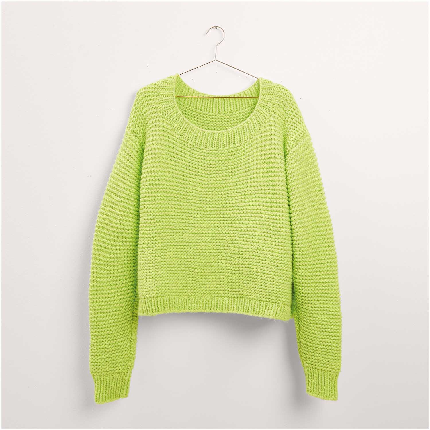 Ein leuchtend grüner Strickpullover von Made by Me, Modell 06, hängt an einem Kleiderbügel. Der Pullover hat ein schlichtes Design mit langen Ärmeln und einem Rundhalsausschnitt. Ideal für kühle Tage.