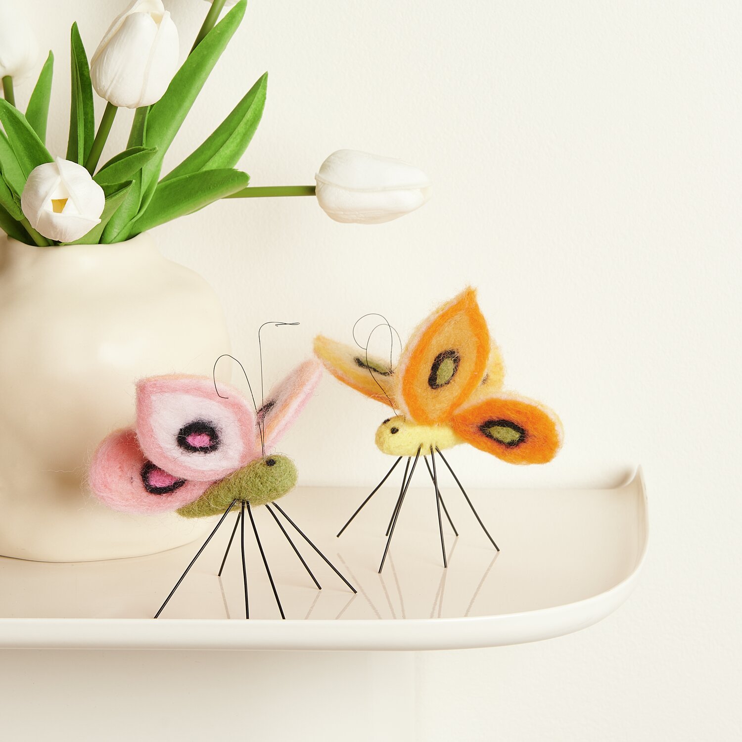 Aufhänger Filz-Schmetterling: Zwei farbenfrohe Filz-Schmetterlinge von Rico Design auf einem Tablett.