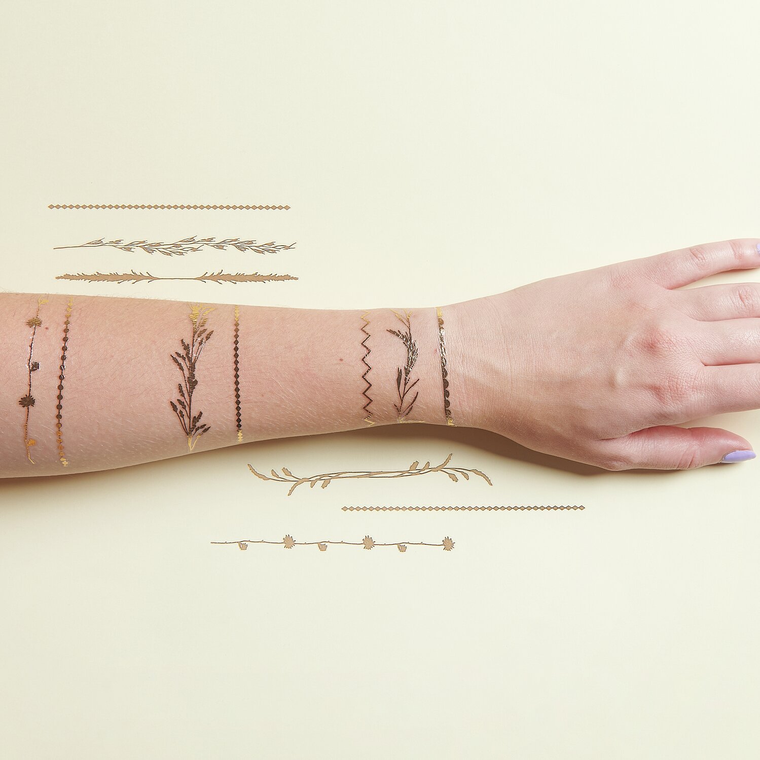 Tattoos Festival Boho: Temporäre Tattoos in Gold und Schwarz auf einem Arm, 12-teiliges Set.