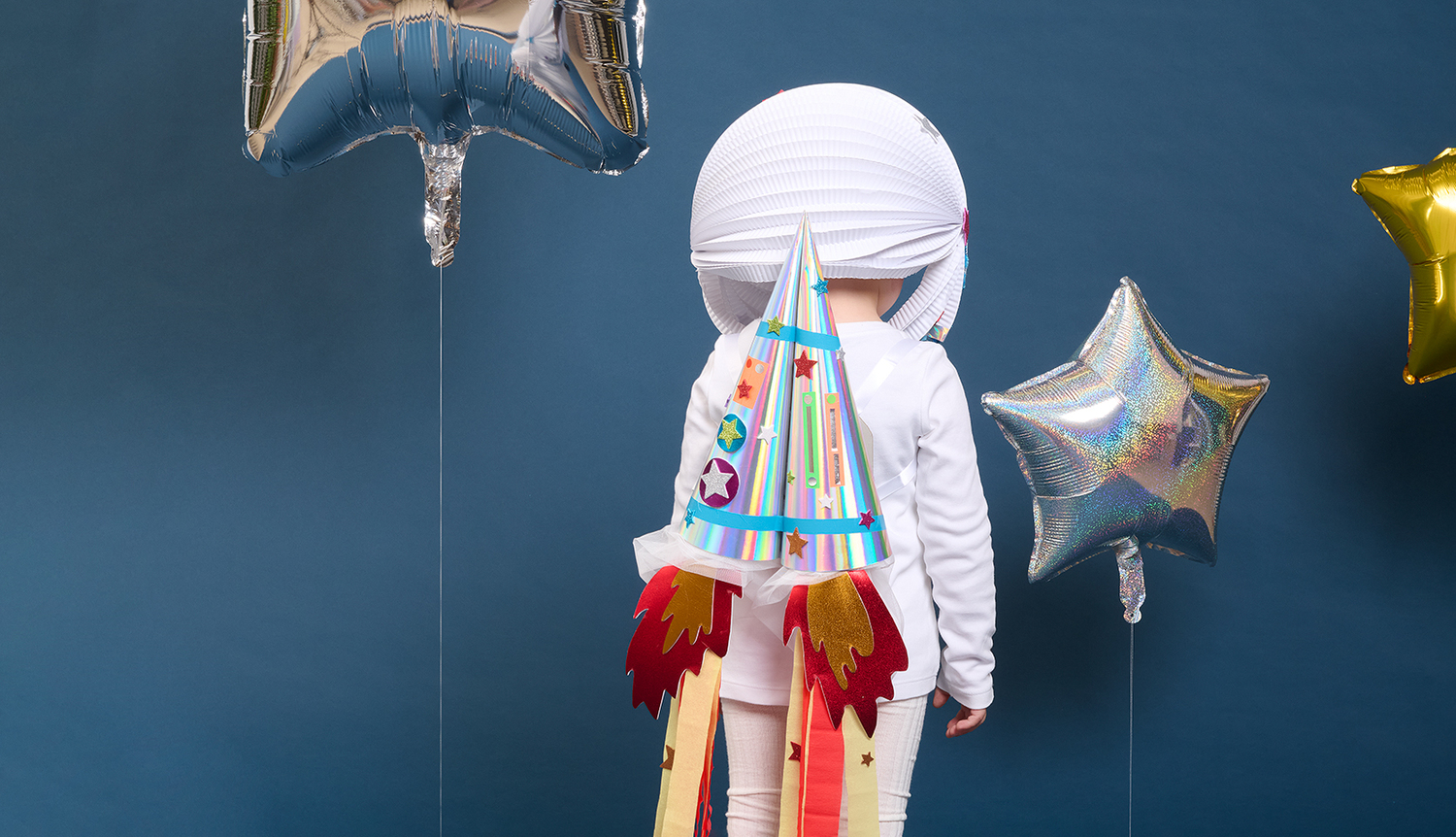 Bastelanleitung Astronauten-Kostüm: Kind in DIY-Raumanzug mit Raketenrucksack vor blauem Hintergrund.