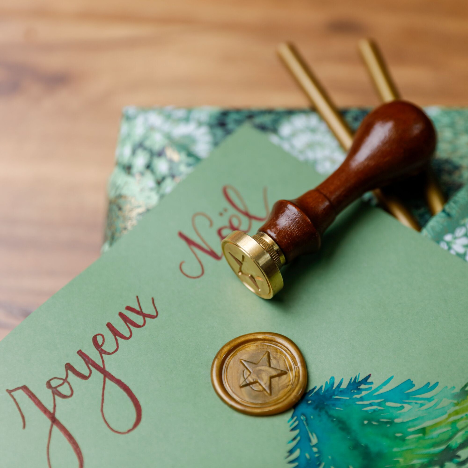 Siegelwachs Stangen, 6-teilig: Goldene Siegelwachs-Stangen mit Holzstempel auf grünem Brief.