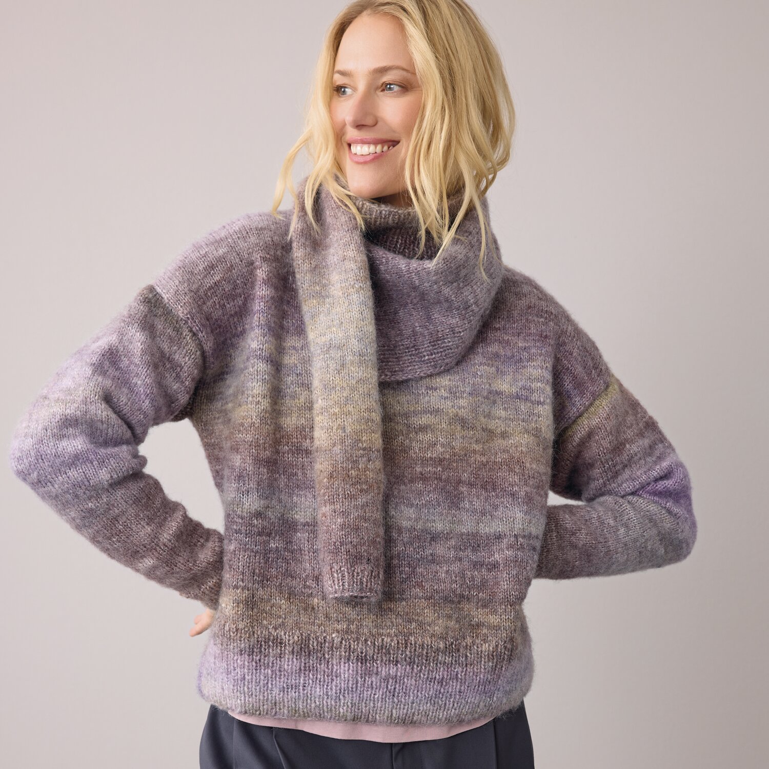 Strickset Pullover Modell 11 aus Die Neue Masche No. 14 von idee. Creativmarkt Strickset Pullover Modell 11 aus DNM 14: Frau trägt lila-braunen Pullover mit passendem Schal.