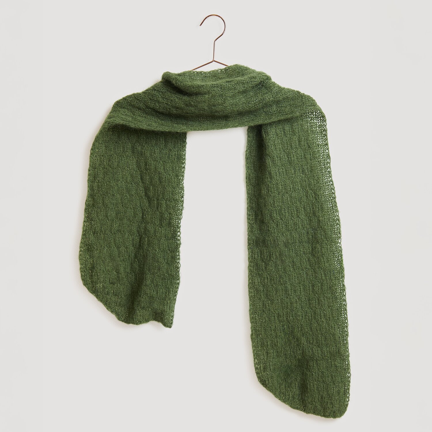 Die Neue Masche No. 13 Herbst von idee. Creativmarkt Strickset Schal Modell 22 aus Die Neue Masche No. 13 in Oliv, gefertigt aus Alpaka-Baumwoll-Mischung, präsentiert auf einem Kleiderbügel.