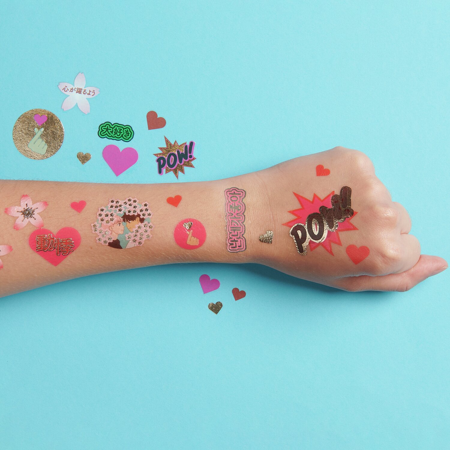 Tattoos Sakura Liebe: Temporäre Tattoos auf einem Arm, bunt gemischt, 24-teilig, auf blauem Hintergrund.