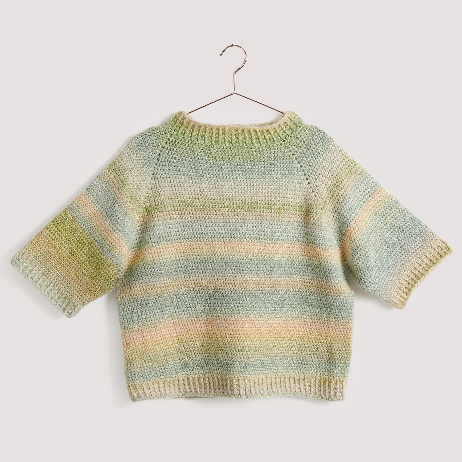 Häkelset Top-Down-Shirt Modell 14, pastellfarben, auf einem Kleiderbügel präsentiert.