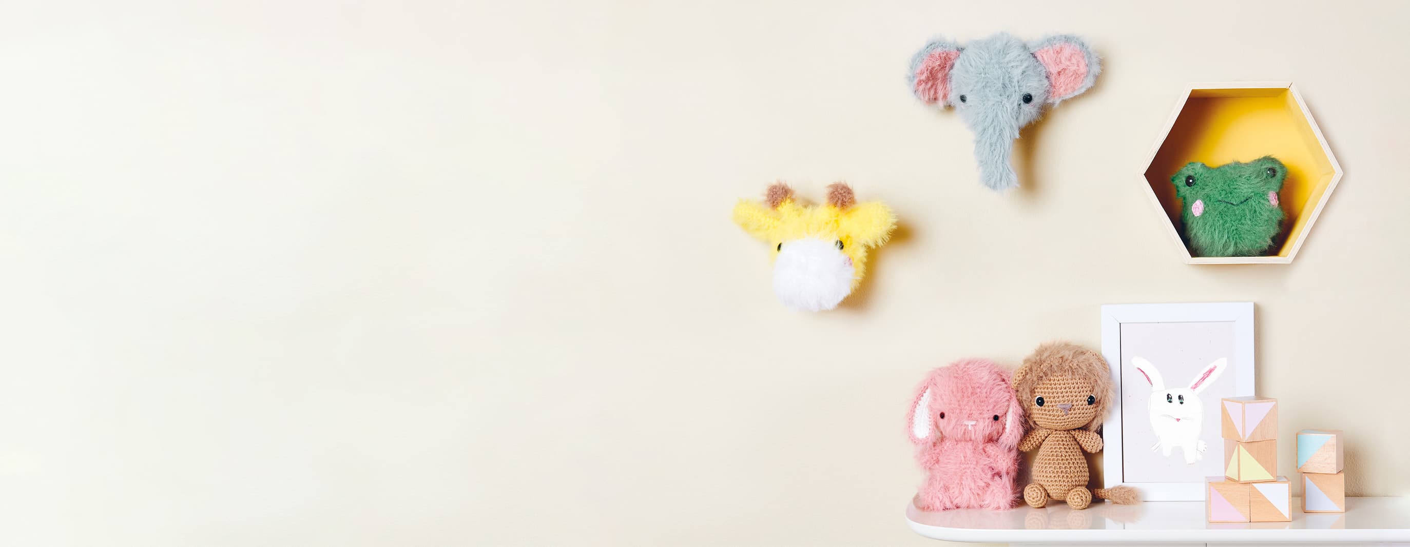 Gehäkelte Tiere mit flauschigem Fell sind an einer Wand und auf einem Regal dekoriert.