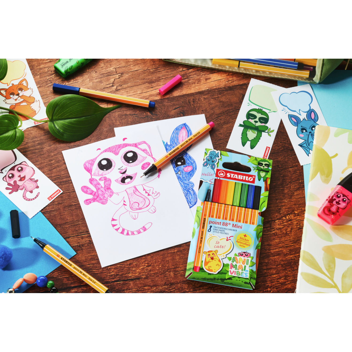 STABILO point 88 Mini Animal Vibes Set 8 Stück zeigt bunte Fineliner beim Ausmalen niedlicher Tiermotive auf einem kreativen Schreibtisch mit Zubehör