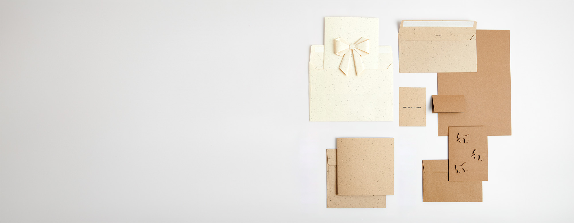 Kraftpapier Karten, teilweise mit Schleifen, und Umschläge übereinandergelegt. Flatlay von Produkten. 
