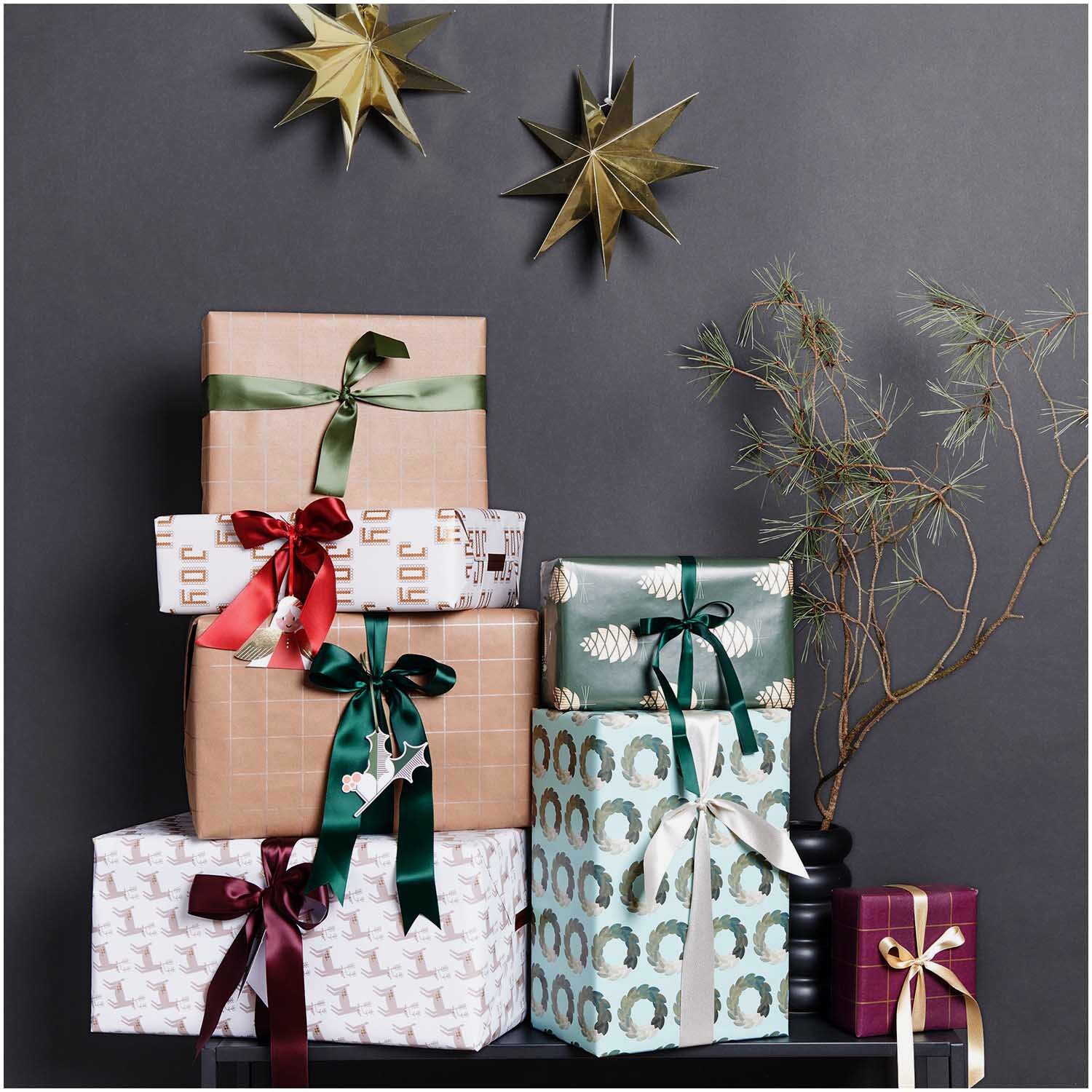 Paper Poetry Satinband 38mm 3m: Elegante Geschenke mit bordeauxfarbenem Band dekoriert, umgeben von festlichen Sternen und Zweigen.