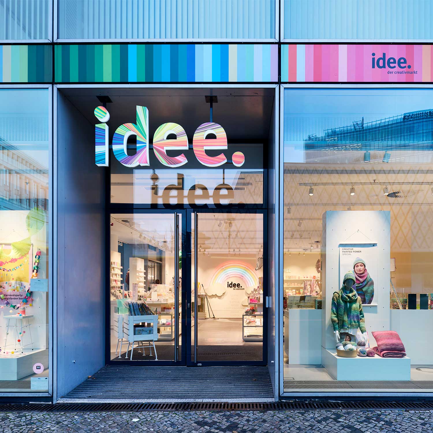 Der Eingang einer idee. Creativmarkt Filiale. Schaufenster mit ausgestellten Produkten und das bunte idee. Logo über der Eingangstür.