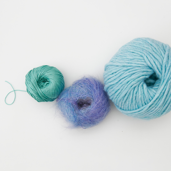 Drei unterschiedliche blaue Knäule nach Größe sortiert. Flatlay von Produkten.