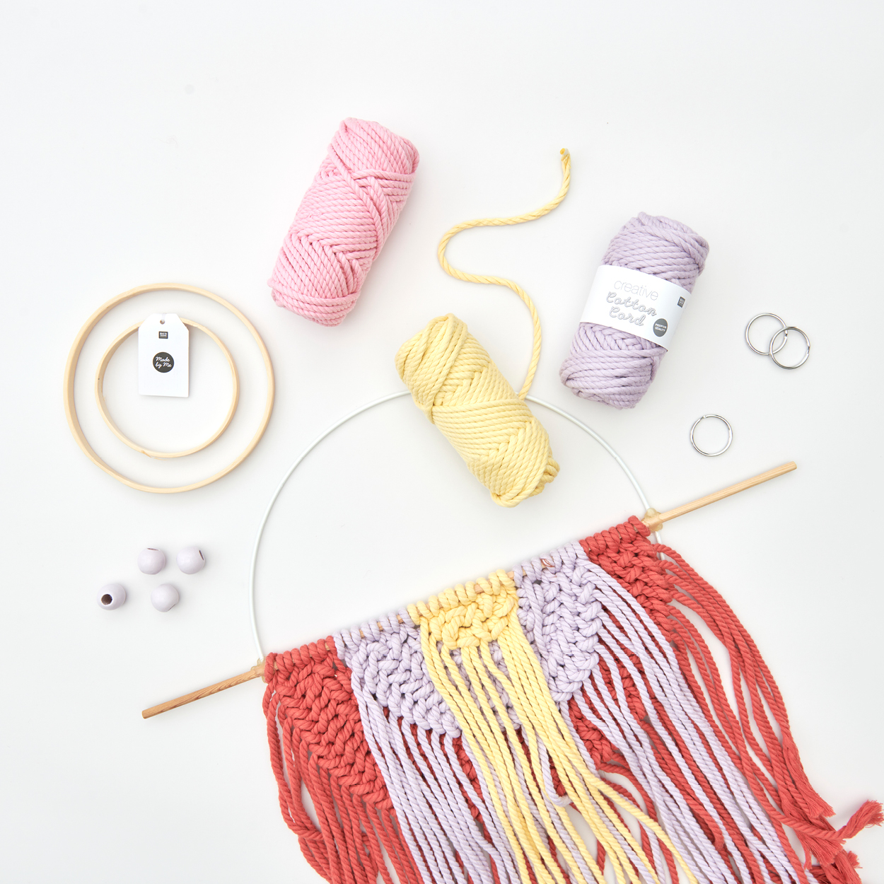 Ein runder Makramee-Wandbehang mit Kordel-Garn, Perlen und Holzringen. Flatlay von Produkten.