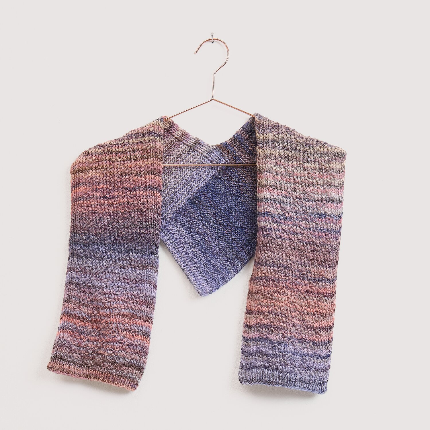 Die Neue Masche No. 16 Herbst, gestrickter Schal von Wolle Rödel in meliertem Lila-Rosa-Grau, locker auf Kupferbügel vor hellem Hintergrund präsentiert