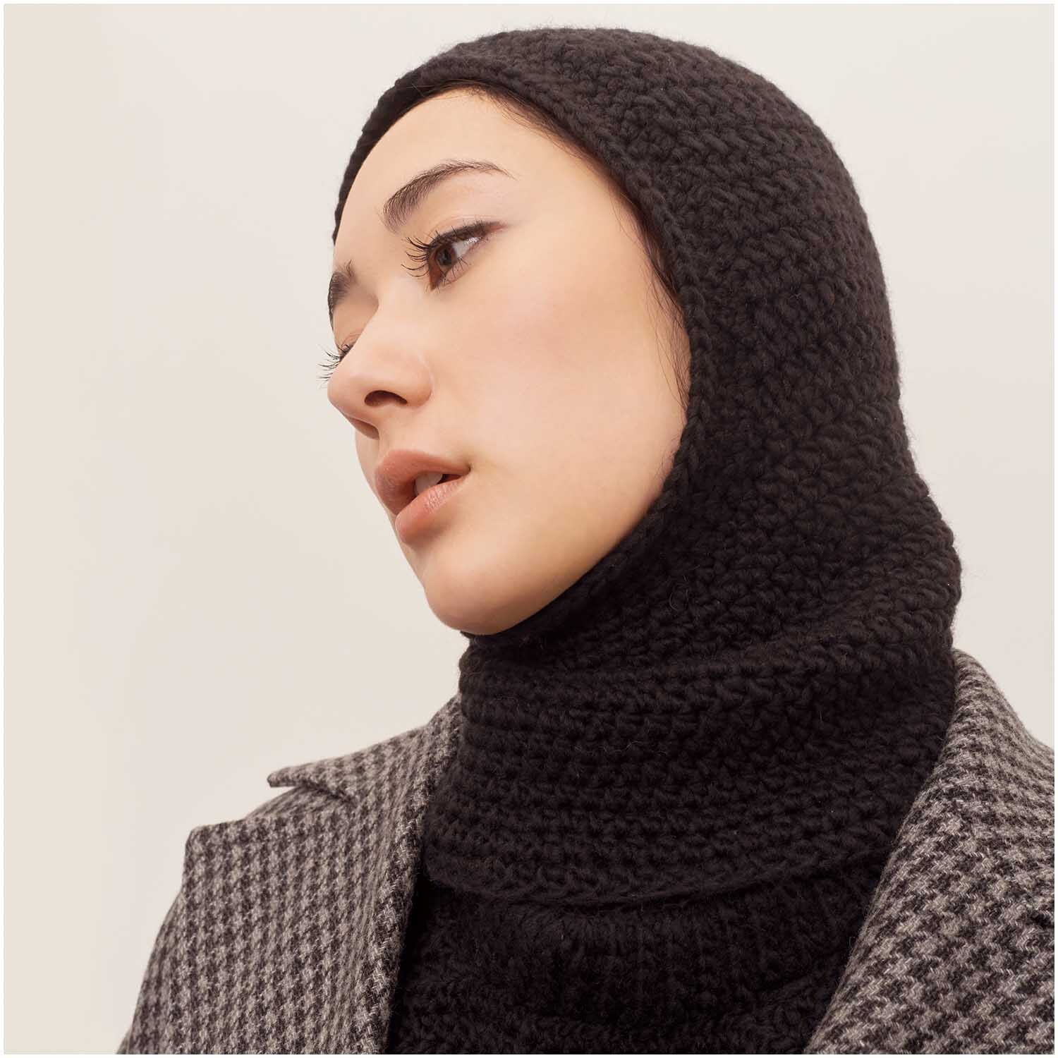 Häkelset Balaklava Modell 11 aus Winter Crochet Collection, schwarze gestrickte Kopfbedeckung, getragen von Person in kariertem Mantel.