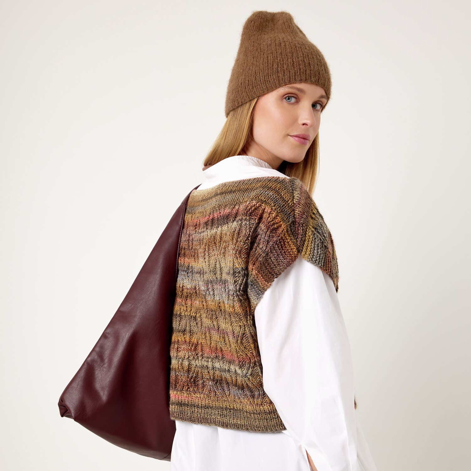 Strickset Mütze Modell 08 aus Die Neue Masche No. 13 von idee. Creativmarkt Strickset Mütze Modell 08: Frau trägt braune Mütze und gemusterten Pullover vor hellem Hintergrund.