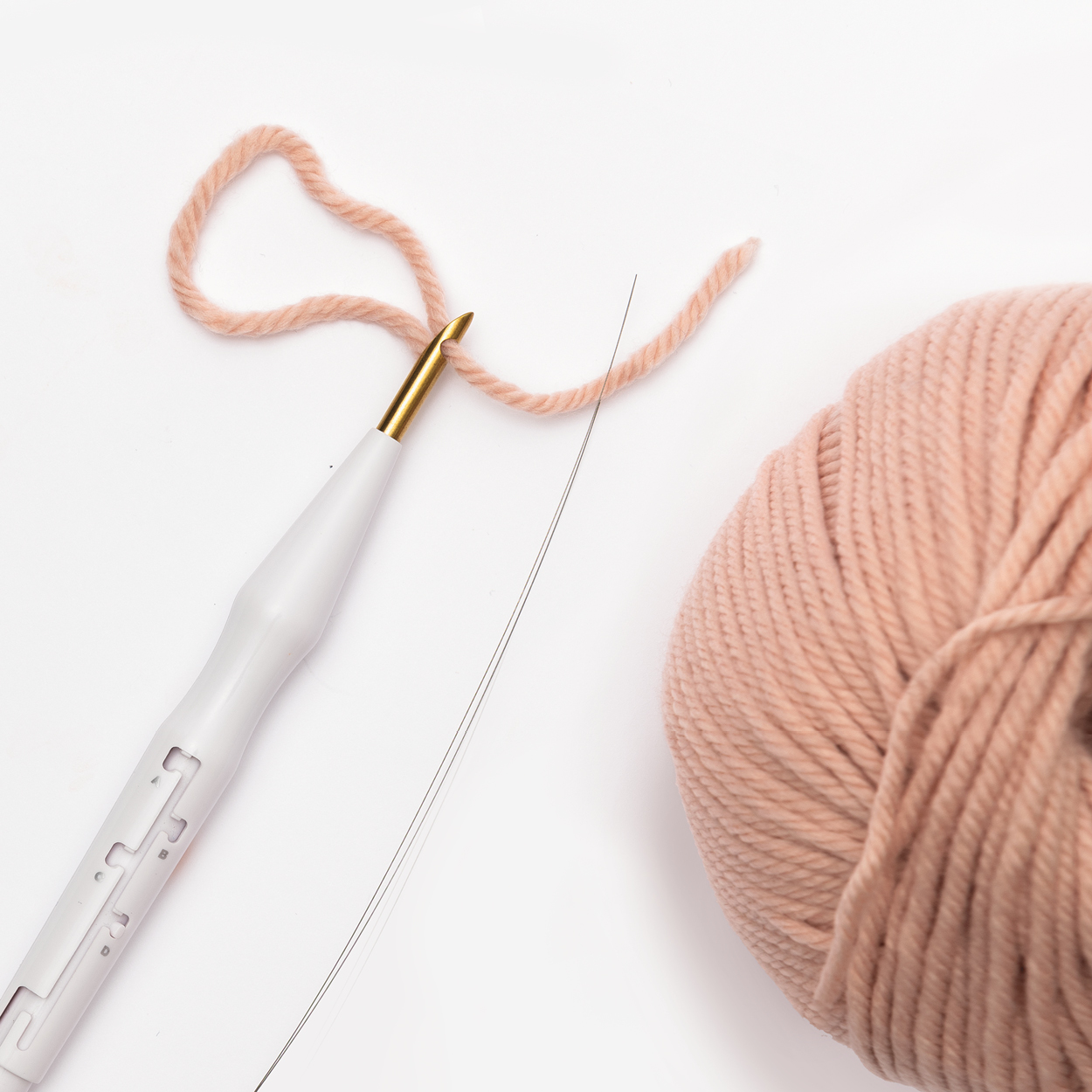 Punch Needle und rosa Wollknäuel auf weißem Hintergrund
