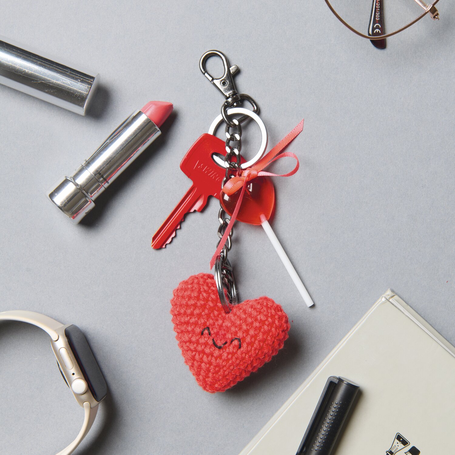 Ricorumi Häkelset Schlüsselanhänger - Chingu Sky: Roter Herzanhänger mit Schleife, Schlüssel und Lippenstift auf grauem Hintergrund.
