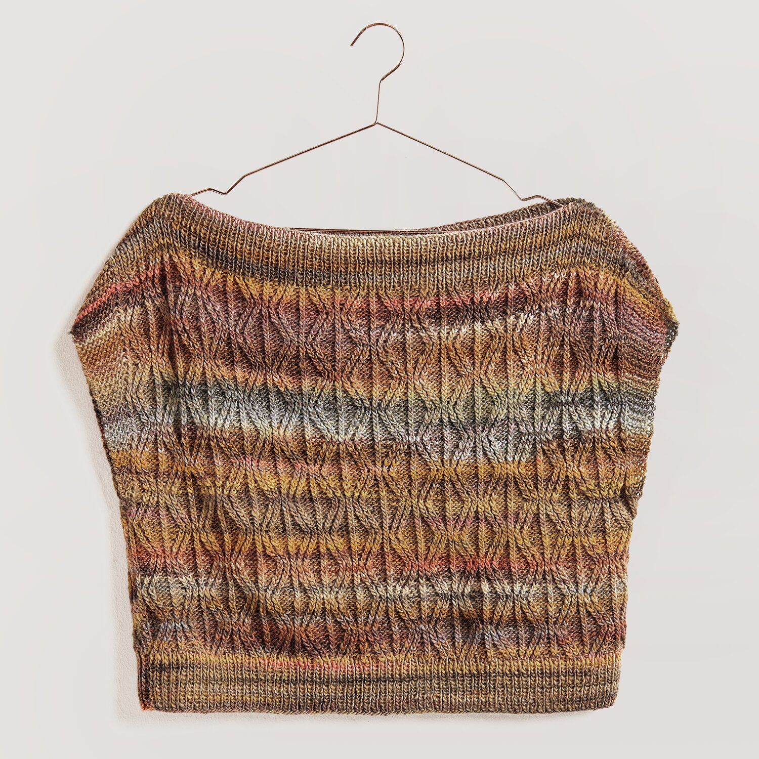 Die Neue Masche No. 13 Herbst von idee. Creativmarkt Strickset Top Modell 17 zeigt ein gestricktes Oberteil in warmen Herbsttönen, aufgehängt an einem Kleiderbügel.