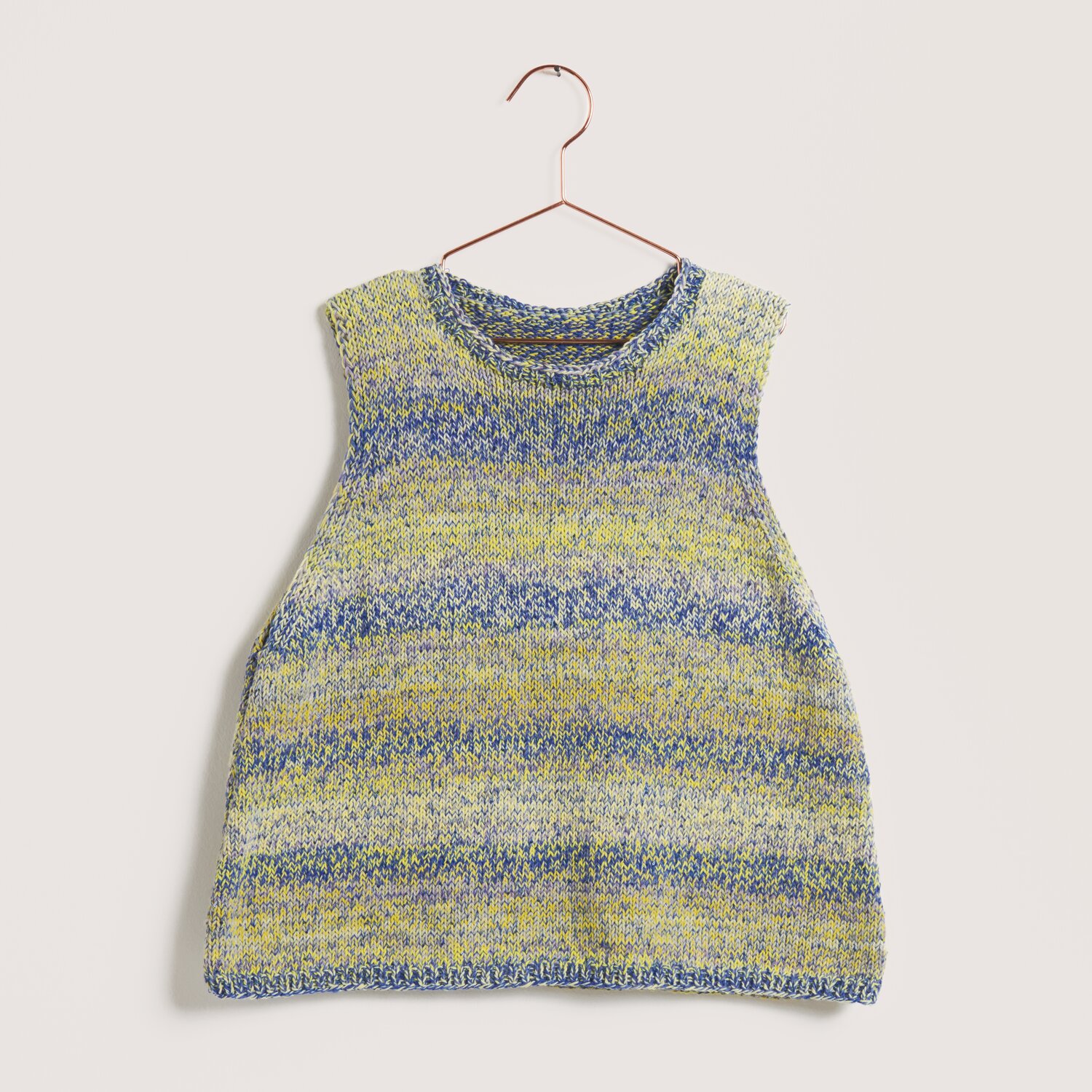Beach: Ärmelloses Stricktop in Blau-Gelb von Rico Design, aufgehängt an einem Kupferbügel.