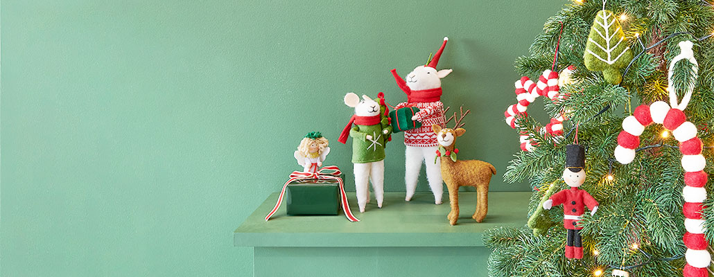 Zwei Filzmäuse, ein Filzhirsch und ein Filzengel, sowie Weihnachtsbaumornamente aus Filz. Fotosetting grünes Regal und Tannenbaum.