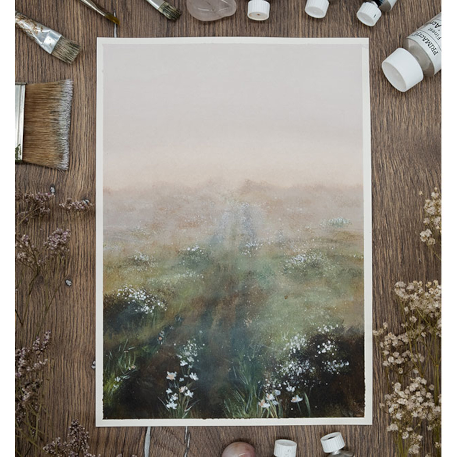 Romantische Natur - Traumlandschaften in Acryl malen: Malerei mit sanften Farben, umgeben von Pinseln und Farbtuben auf Holztisch.