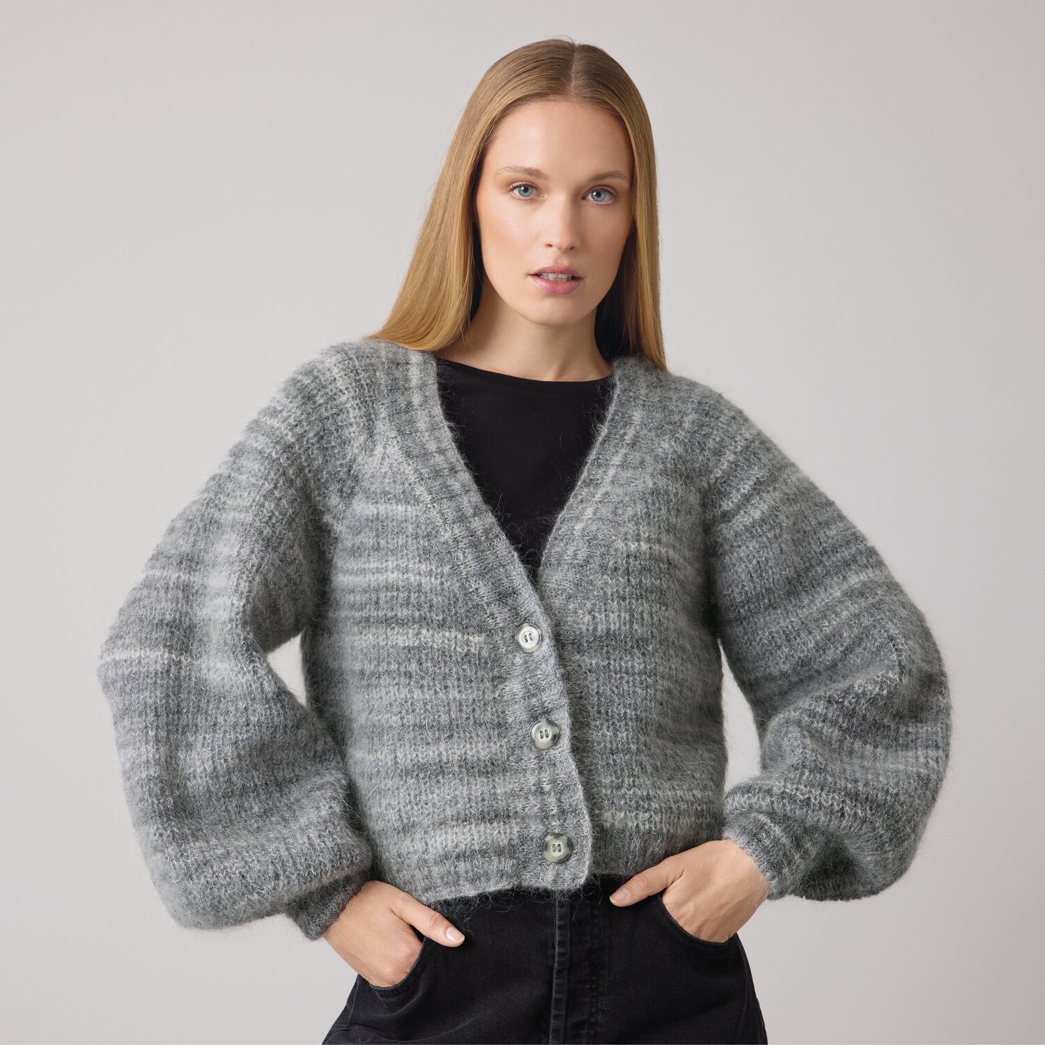 Strickset Jacke Modell 15 aus Die Neue Masche No. 14 von idee. Creativmarkt Strickset Jacke Modell 15 aus DNM 14: Graue, flauschige Strickjacke mit Knöpfen, getragen von Frau.