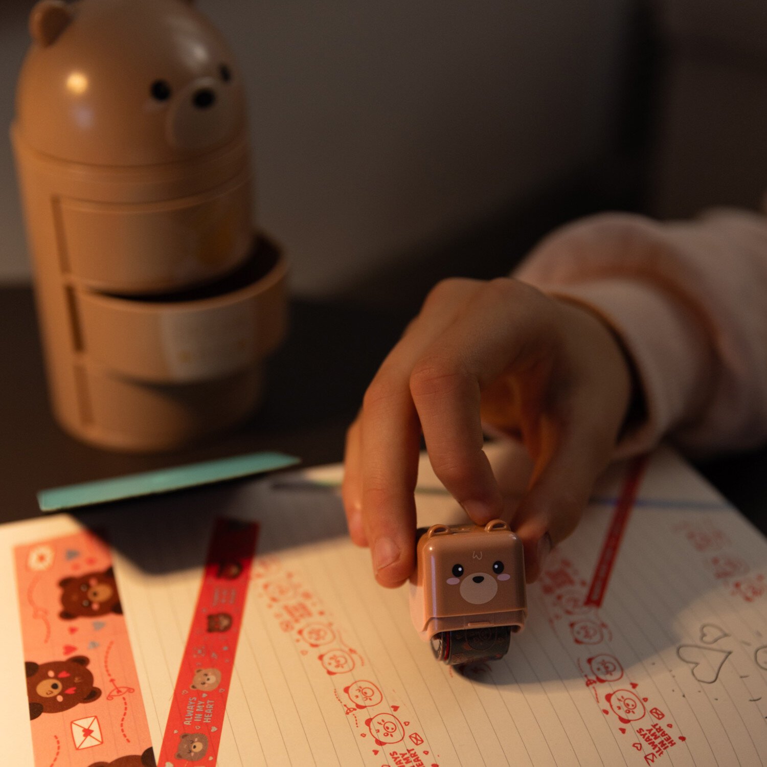 Deco Roller Stempel von Legami mit Teddy-Bear-Design, brauner Bären-Roller dekoriert liebevoll ein Notizblatt mit roten Motivreihen und süßen Symbolen