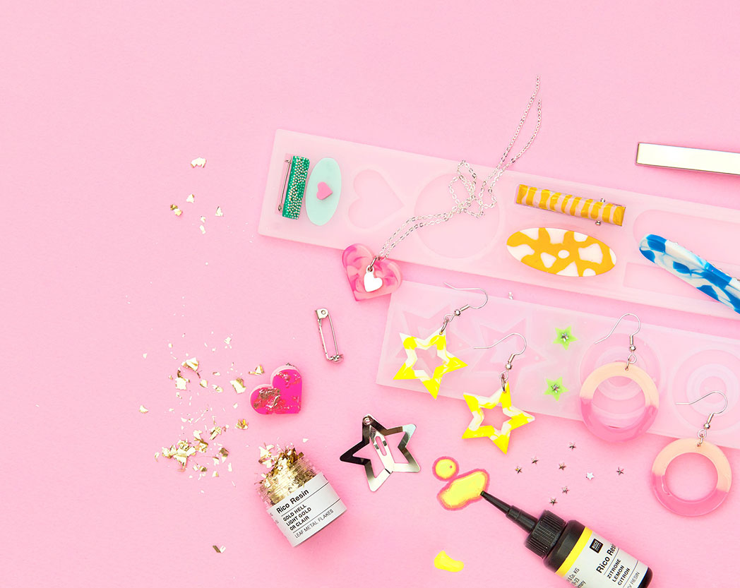 Bunte Ohrringe und Haarspangen aus Resin gegossen mit passender Silikonform, Resin und Füllmaterial. Flatlay von Produkten.