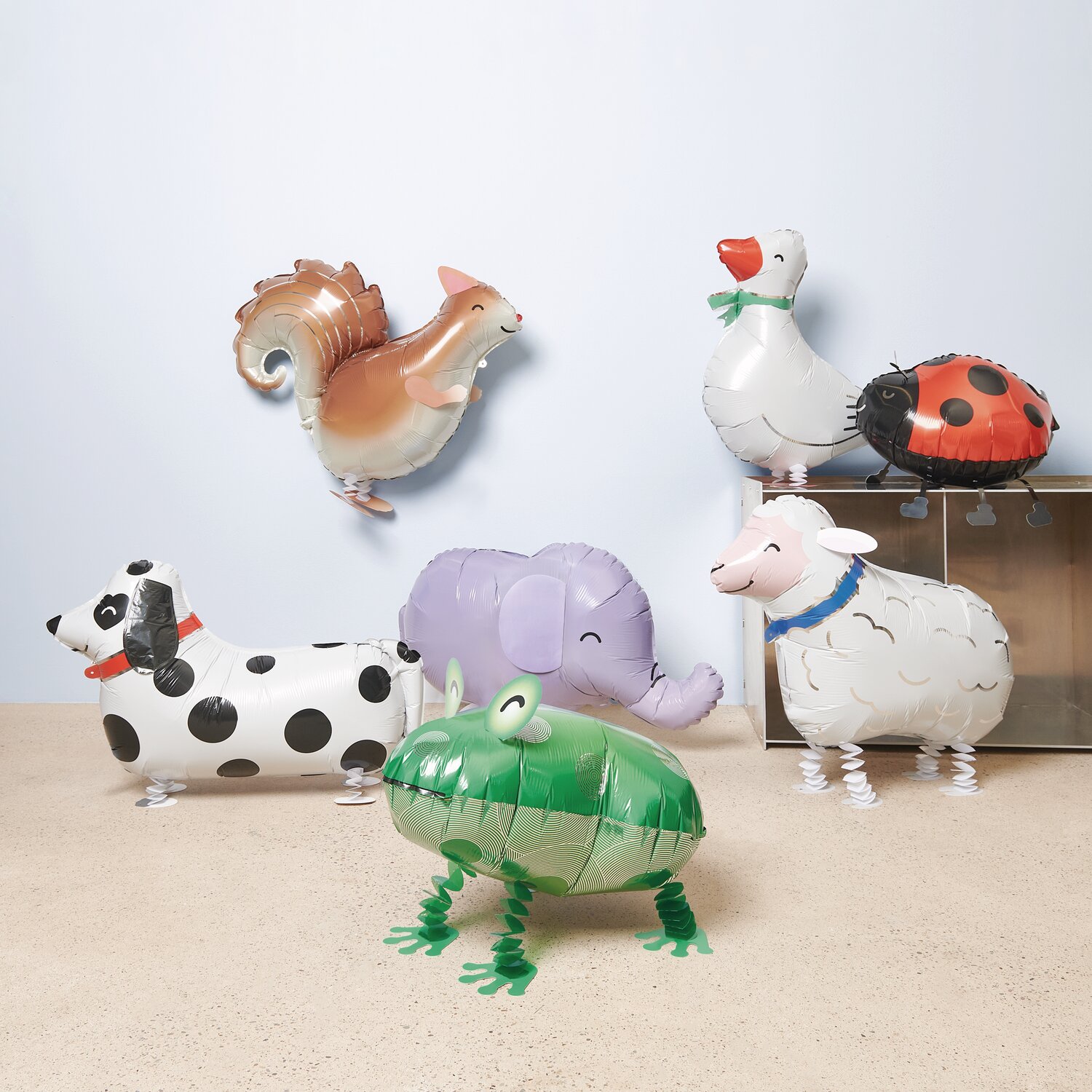 Folienballon Airwalker Eichhörnchen, Schaf, Marienkäfer, Frosch, Dalmatiner und Gans in verschiedenen Farben auf hellem Boden.