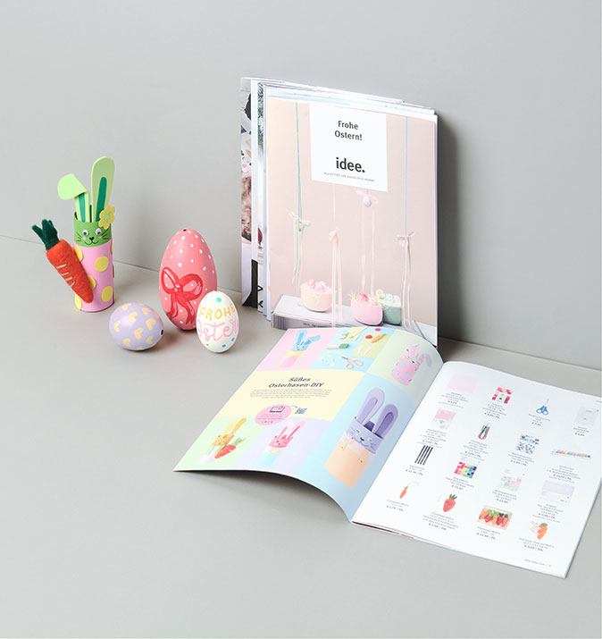 idee. Prospekt liegt in grauer Ecke mit Osterdeko daneben