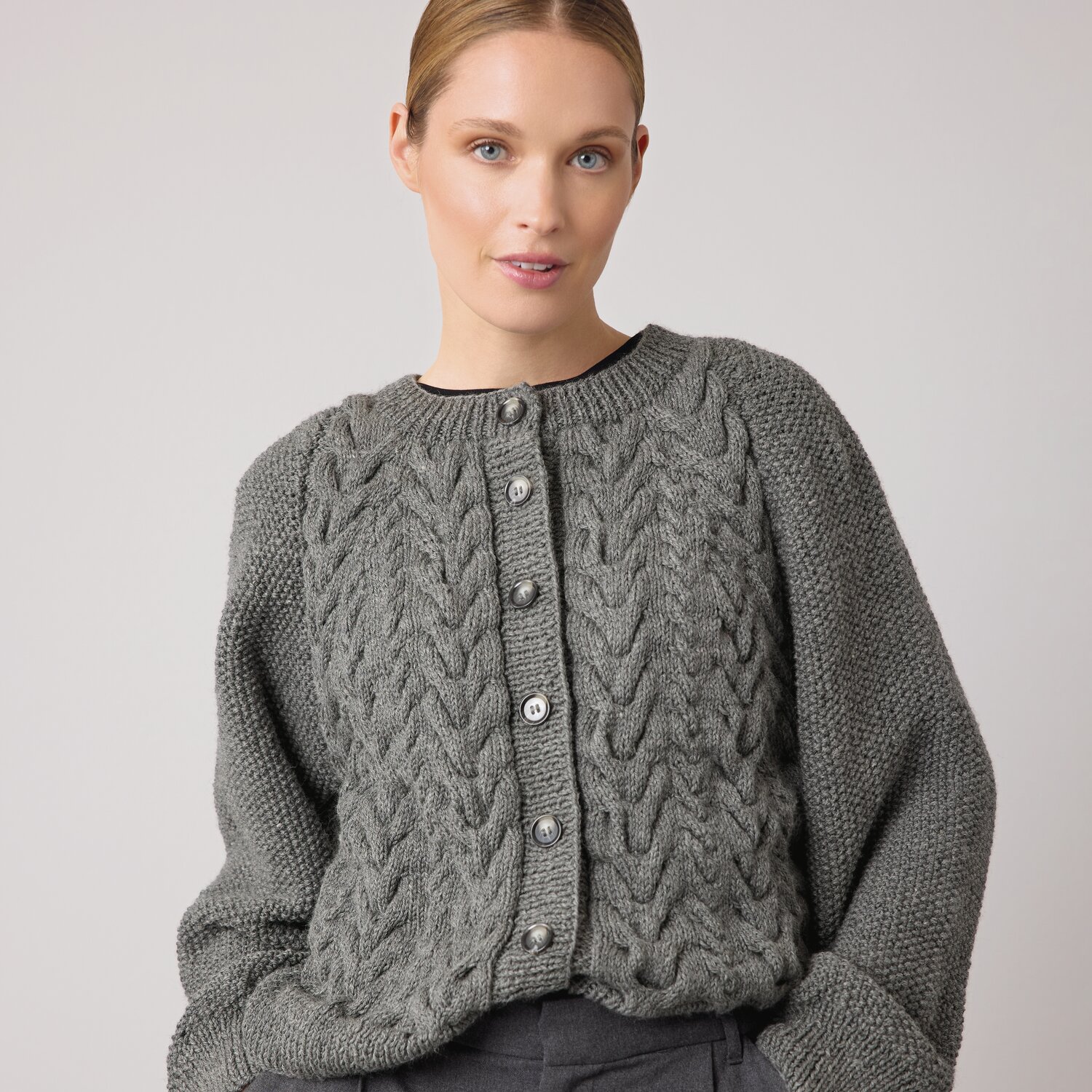 Strickset Jacke Modell 25 aus Die Neue Masche No. 14 von idee. Creativmarkt Strickset Jacke Modell 25 aus DNM 14, graue Strickjacke mit Zopfmuster und Knopfleiste, elegant und stilvoll für kühle Tage.