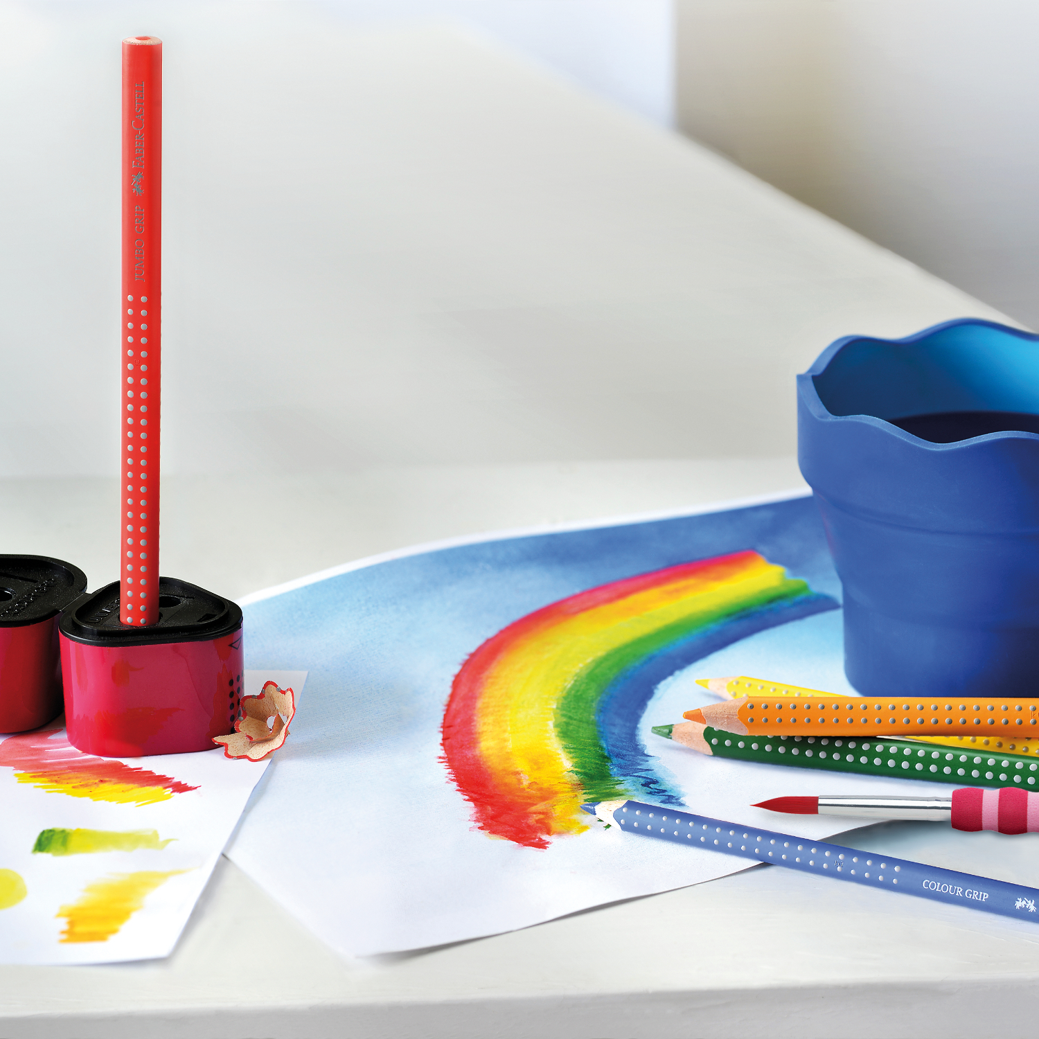 Jumbo Grip Farbstift von Faber Castell in einer kreativen Szene mit Regenbogenzeichnung und weiteren Stiften.