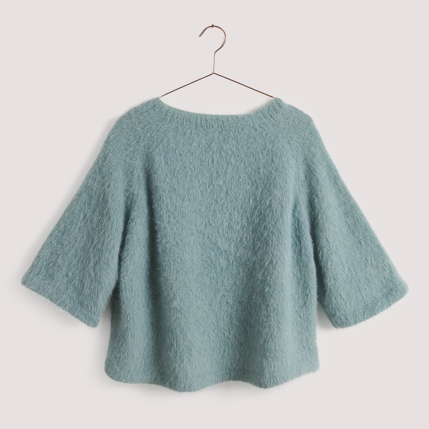 Strickset Shirt Modell 27 aus Die Neue Masche No. 15, flauschiges Oberteil in sanftem Blau, auf einem Kleiderbügel vor neutralem Hintergrund.