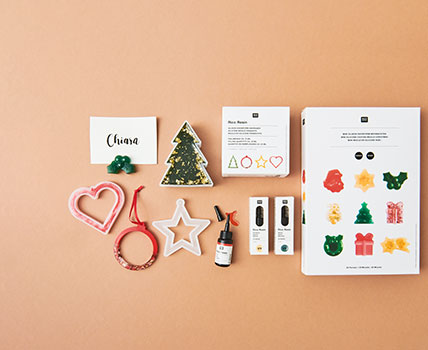 Weihnachtliche Silikonformen mit Resin und fertigen Weihnachtsbaumanhängern aus Resin. Flatlay von Produkten.