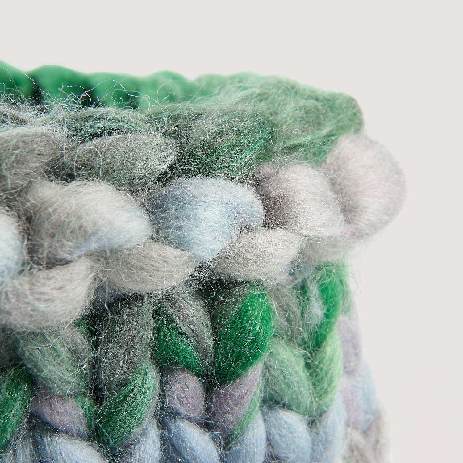 Die Neue Masche No. 16 Herbst zeigt grob gestricktes, mehrfarbiges Körbchen aus Wolle Rödel mit weichen, voluminösen Maschen in Grün-, Blau- und Grautönen.