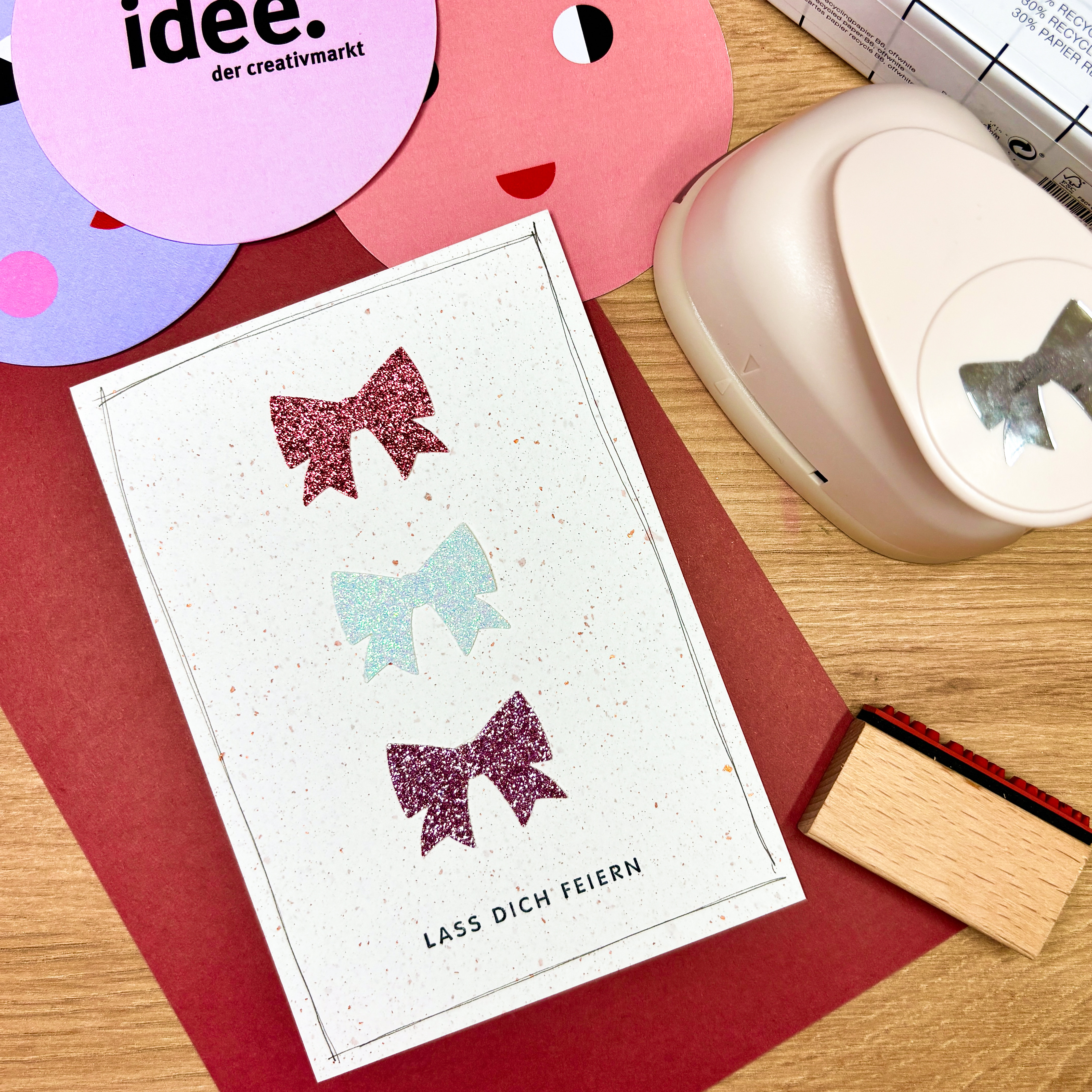 Eine Karte mit drei übereinander angeordneten Schleifen in unterschiedlichen Farben und darunter ein Schriftzug.