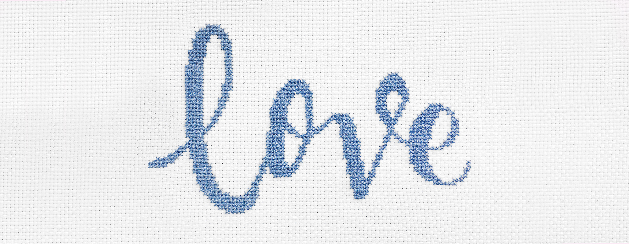 Das Wort "Love" ist im gezählten Kreuzstich-Muster auf Stramin gestickt