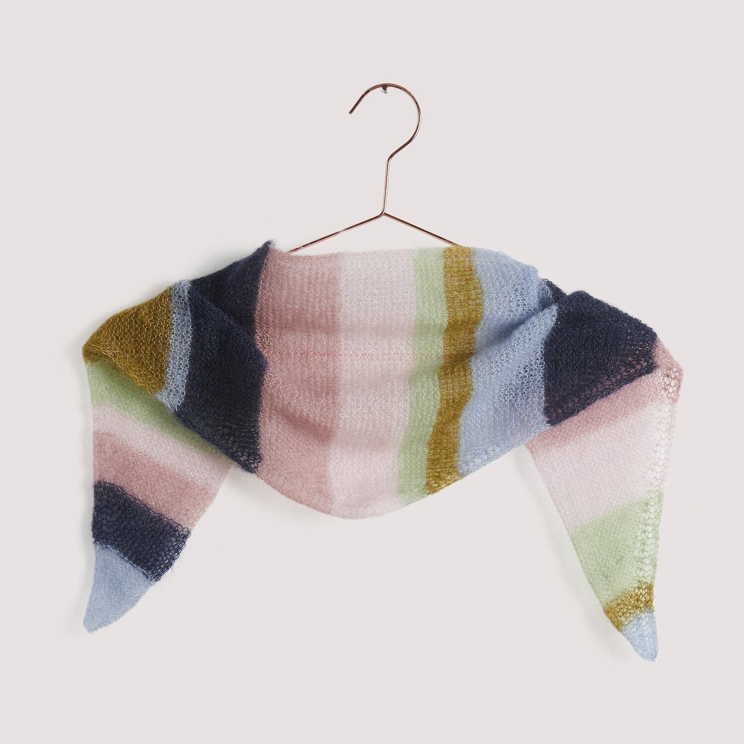 Strickset Dreieckstuch Modell 12 A: Weiches, mehrfarbiges Tuch aus pastellfarbenem Garn, präsentiert auf einem Kleiderbügel.
