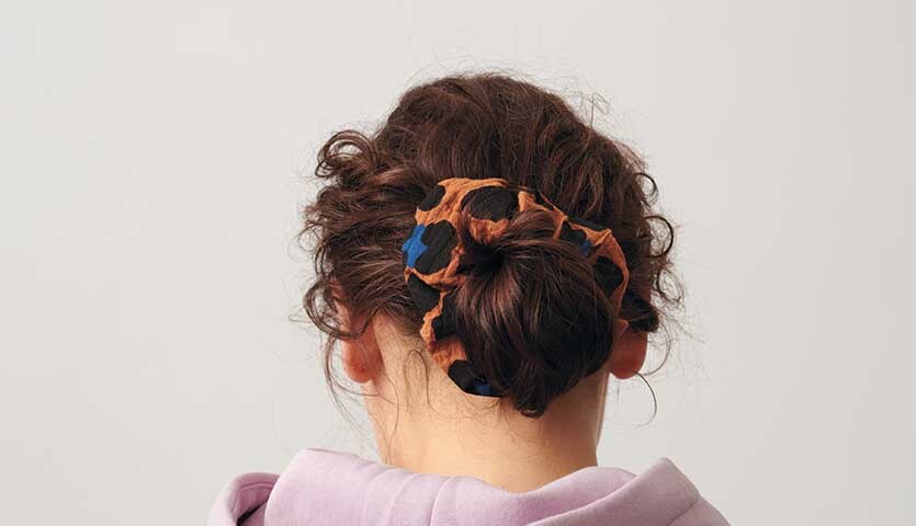 Nähanleitung für Scrunchies aus Stoff Nähanleitung für Scrunchies aus Stoff: Frau mit lockigem Haar trägt bunten Scrunchie im Dutt.