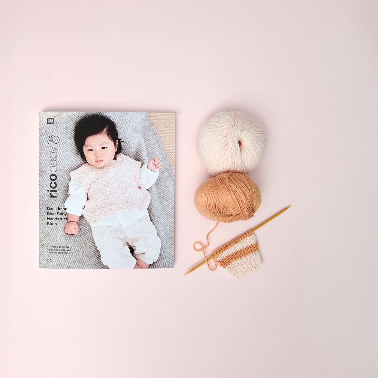 Rico-Baby-Heft daneben zwei Garne in unterschiedlichen Farben