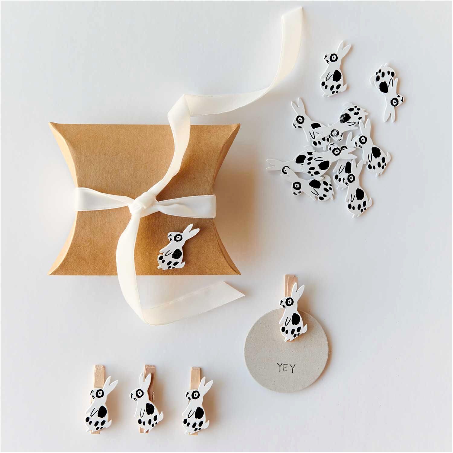 Holzsticker Hase gemustert 12 Stück: Weiße Hasensticker und Clips neben einer Geschenkbox.